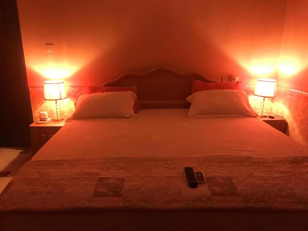 a bedroom with a large white bed with two lamps at JEMP INN HOTEL in Asamankese