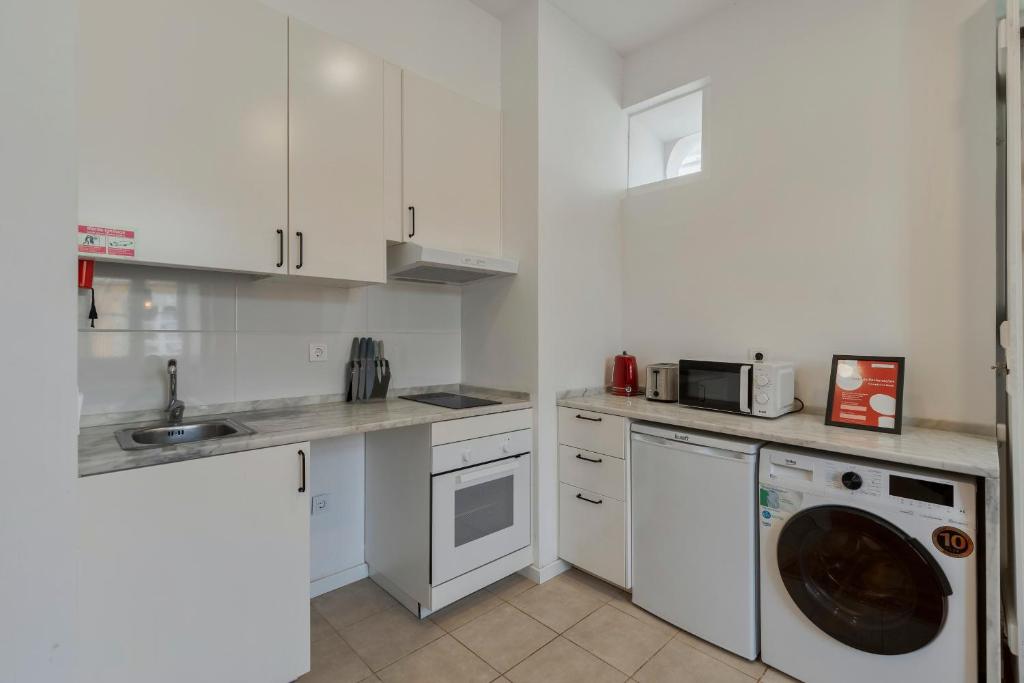 a kitchen with white cabinets and a washing machine at Setubal Seaside in Setúbal