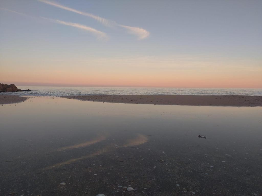 a beach with a reflection of the sky in the water at Villa Tahitienne in Frontignan
