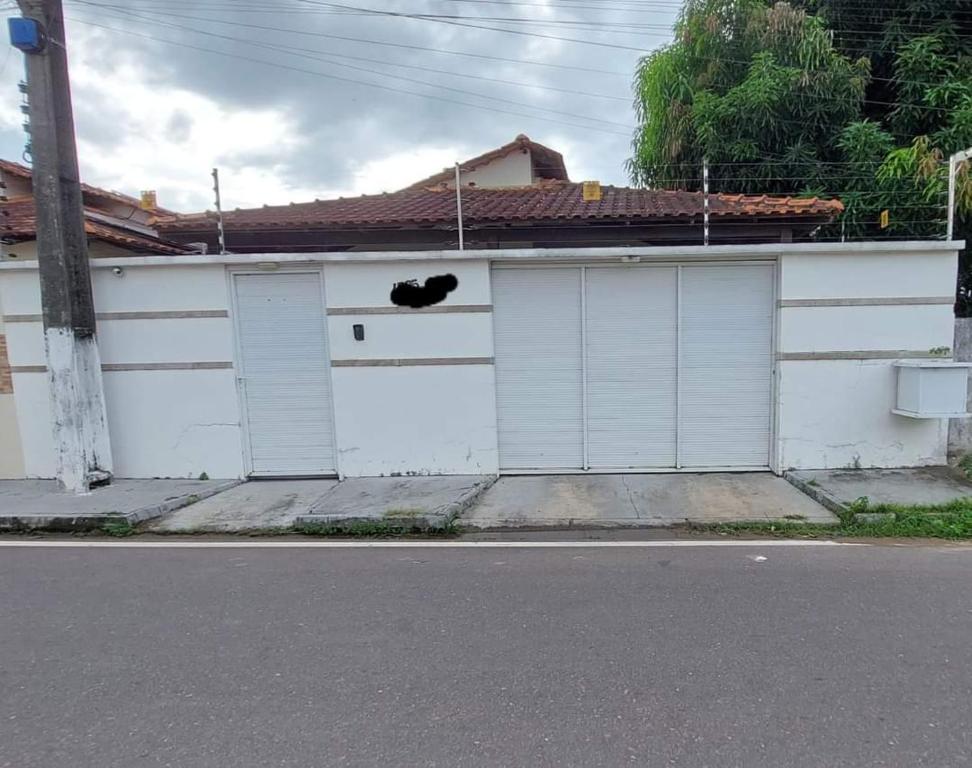a white garage with two doors and a black cat sitting on top at Casa Mobiliada para o período do Festival Folclórico de Parintins 2024 in Parintins