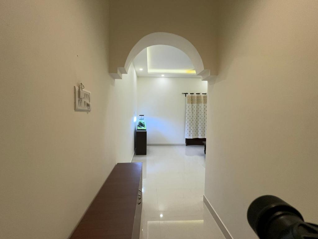 a room with a hallway with an archway at Maple Grove Traditional Homes. in Bangalore