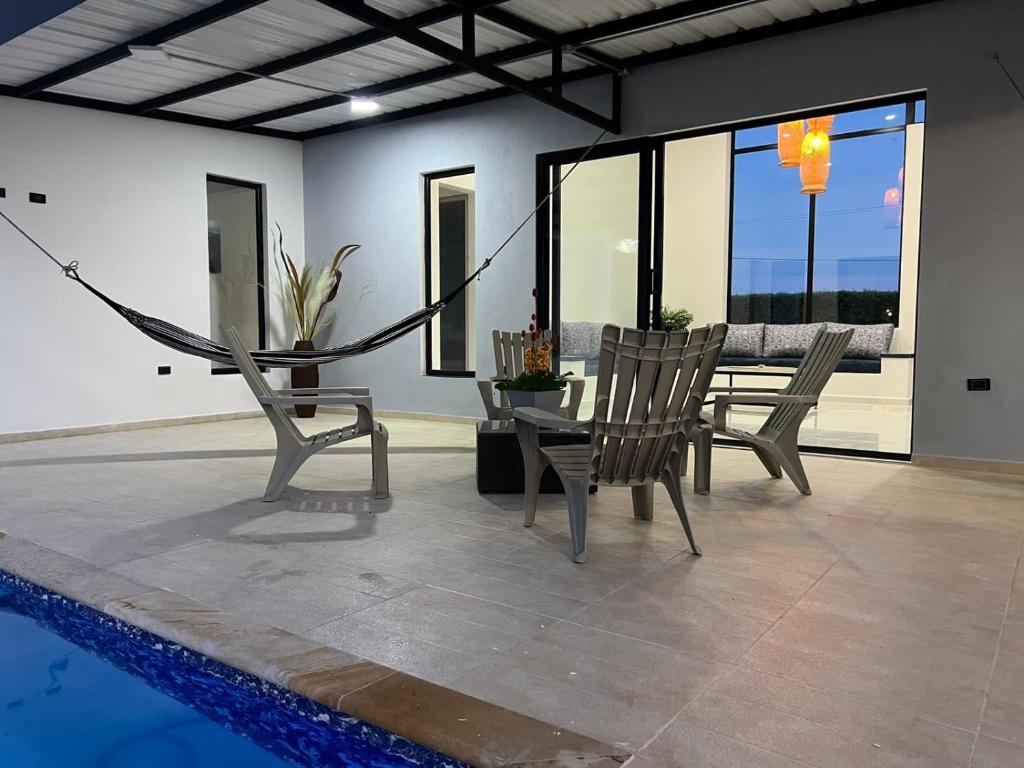 a patio with a hammock and chairs next to a pool at PALO ALTO - EXCLUSIVA CASA DE CAMPO in Restrepo