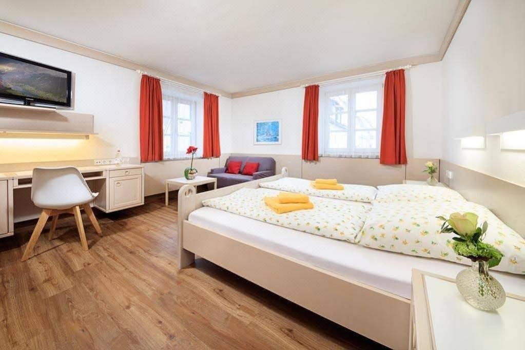 a bedroom with a bed and a desk and a tv at Hotel und Gasthof Zur Laute in Mindelheim