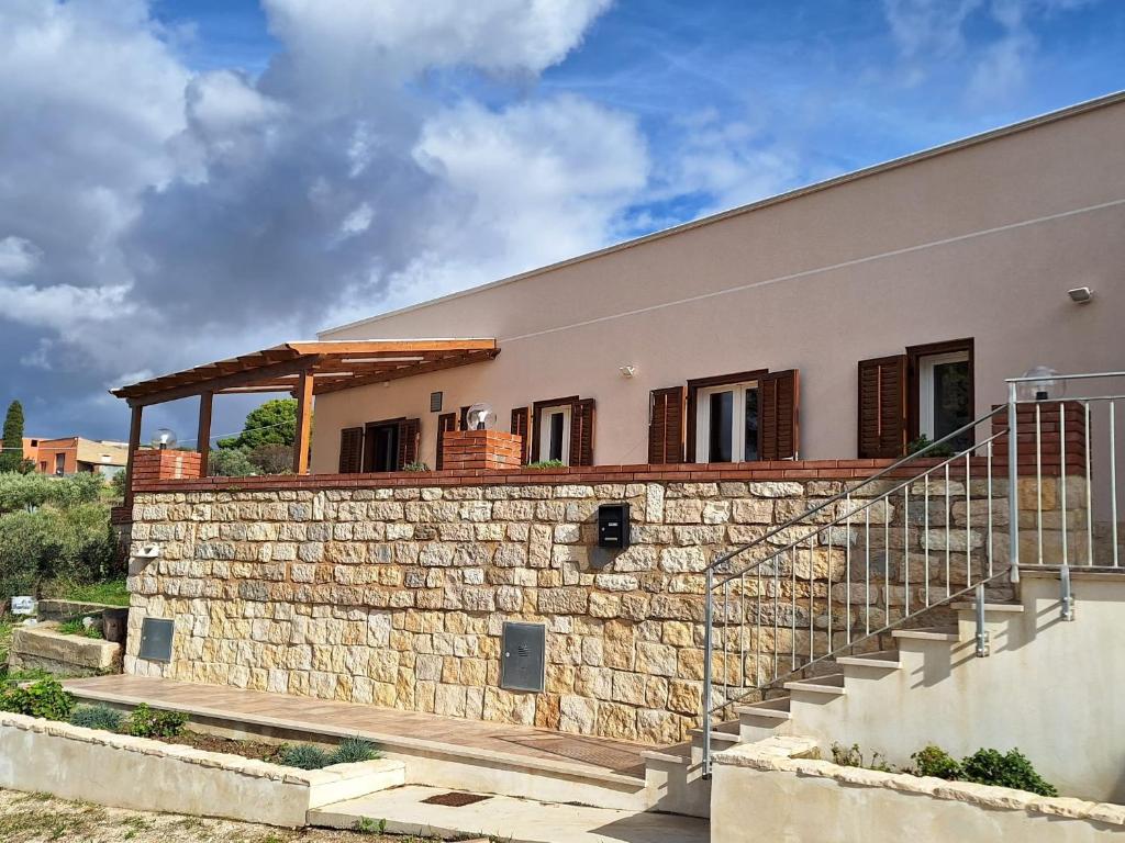 a house with a stone wall and a staircase at Case Vacanza Pianoneve in Buseto Palizzolo