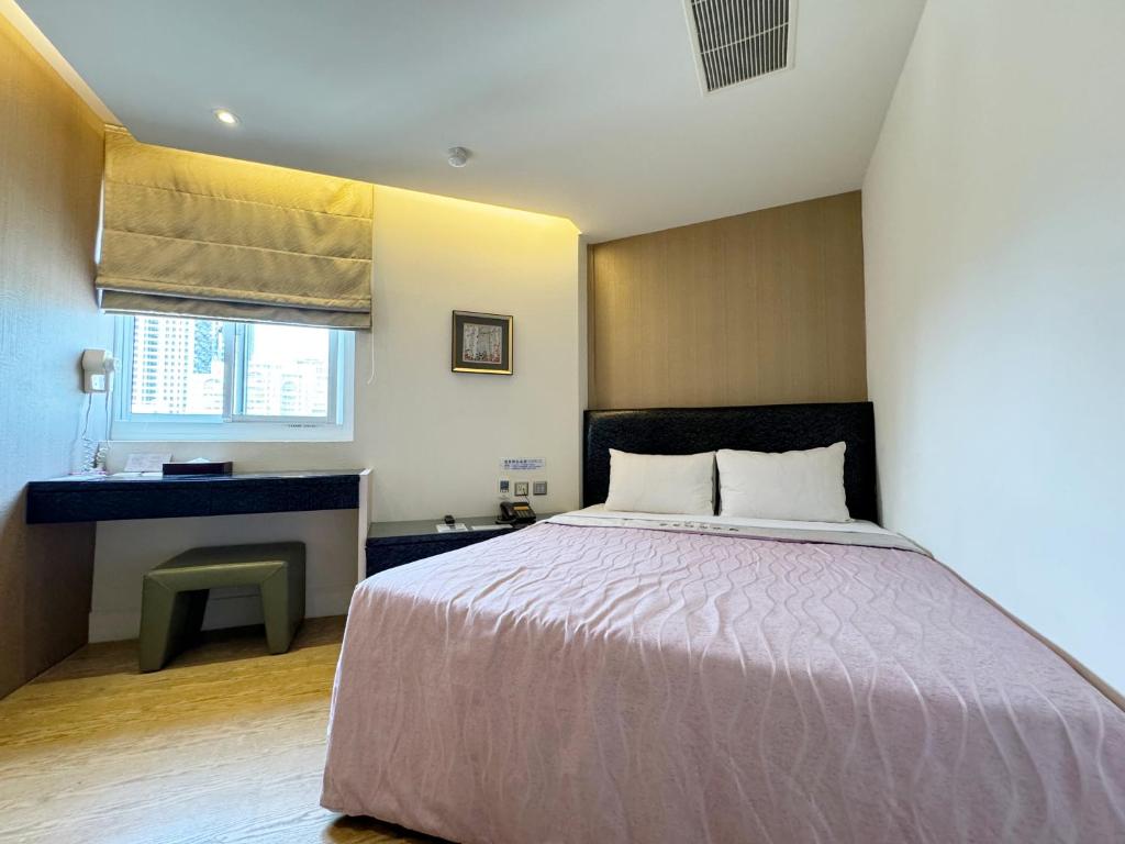 a bedroom with a bed and a desk and a window at Ai Lai Fashion Hotel in Taichung