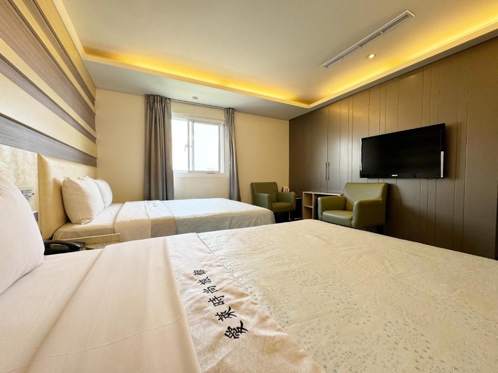 a hotel room with two beds and a flat screen tv at Ai Lai Fashion Hotel in Taichung