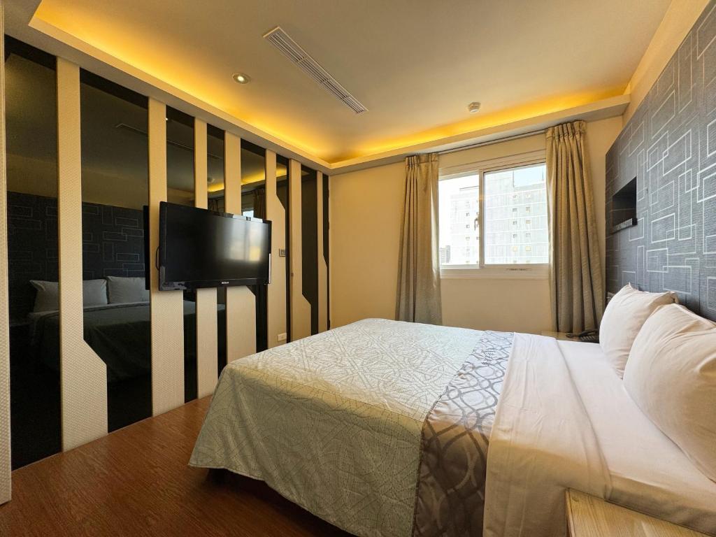 a bedroom with a bed and a flat screen tv at Ai Lai Fashion Hotel in Taichung
