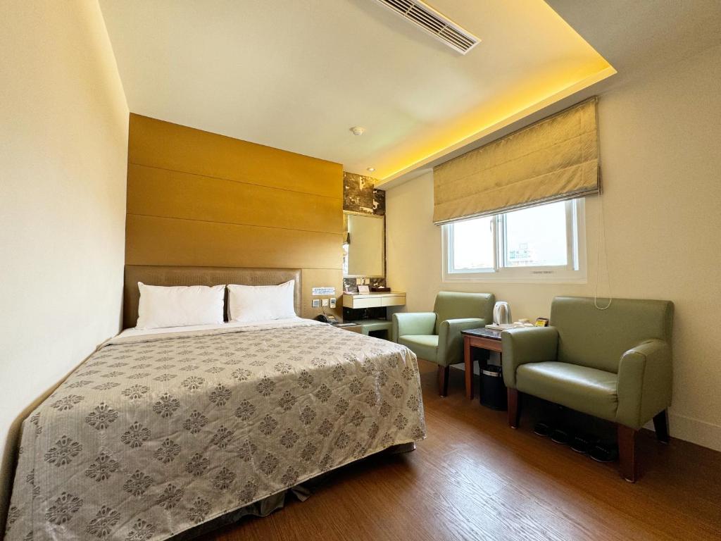 a bedroom with a bed and two chairs and a desk at Ai Lai Fashion Hotel in Taichung