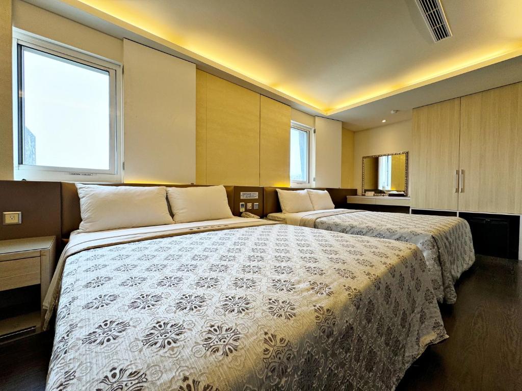 a hotel room with two beds and two windows at Ai Lai Fashion Hotel in Taichung