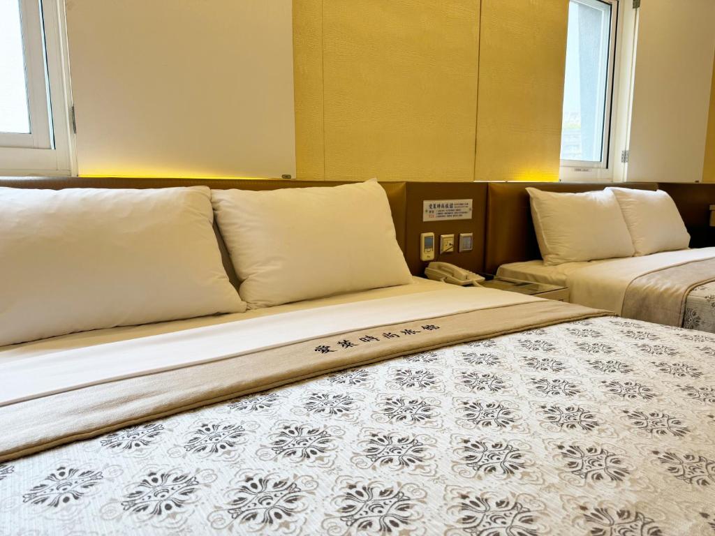 a bedroom with two beds and two windows at Ai Lai Fashion Hotel in Taichung