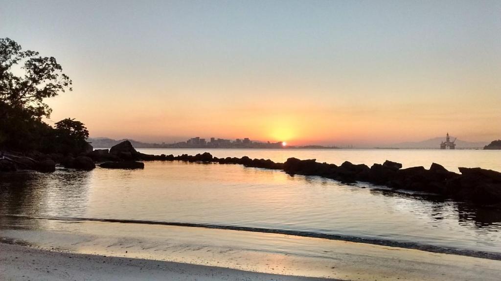 um pôr-do-sol sobre um corpo de água com pedras em Farol do cais em Niterói