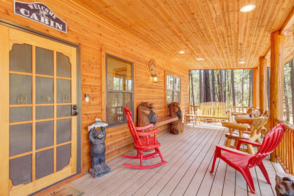 a cabin with red rocking chairs on a wooden porch at Rustic Lakeside Cabin on 3 Acres w/ Nature Views! in Pinetop-Lakeside