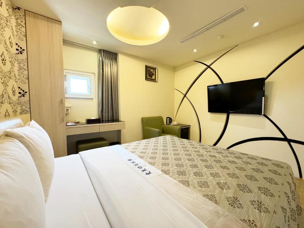 a hotel room with a bed and a flat screen tv at Ai Lai Fashion Hotel in Taichung