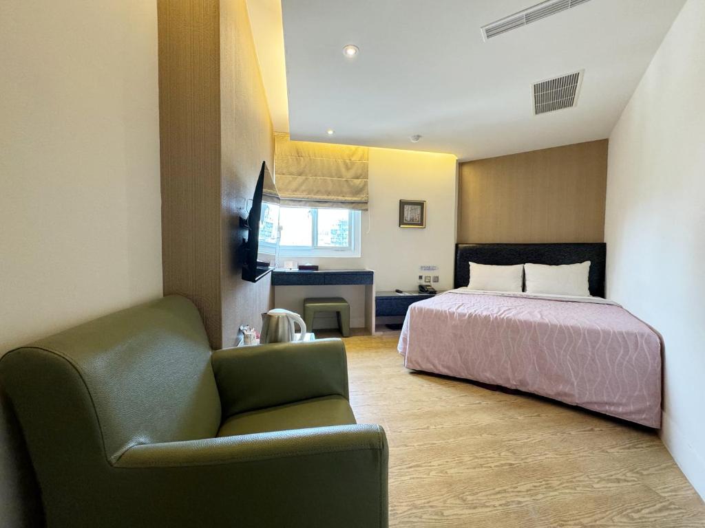 a hotel room with a bed and a chair at Ai Lai Fashion Hotel in Taichung