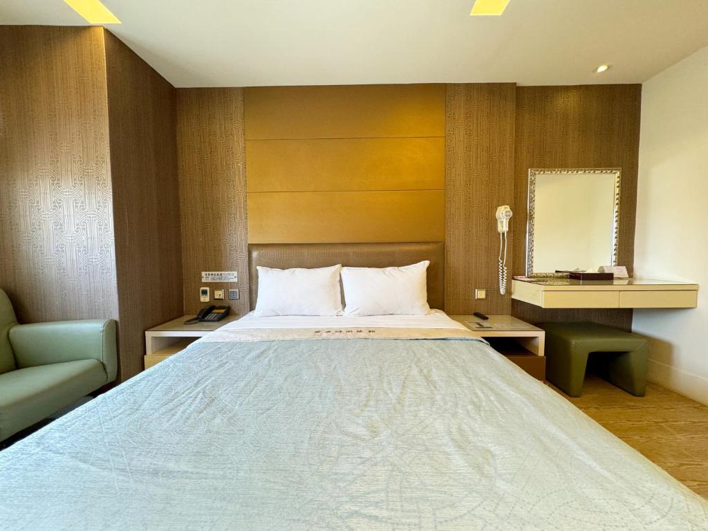 a bedroom with a large bed and a chair at Ai Lai Fashion Hotel in Taichung