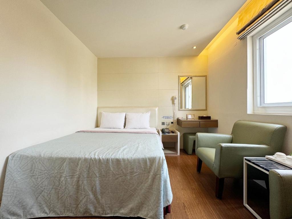 a bedroom with a bed and a chair at Ai Lai Fashion Hotel in Taichung