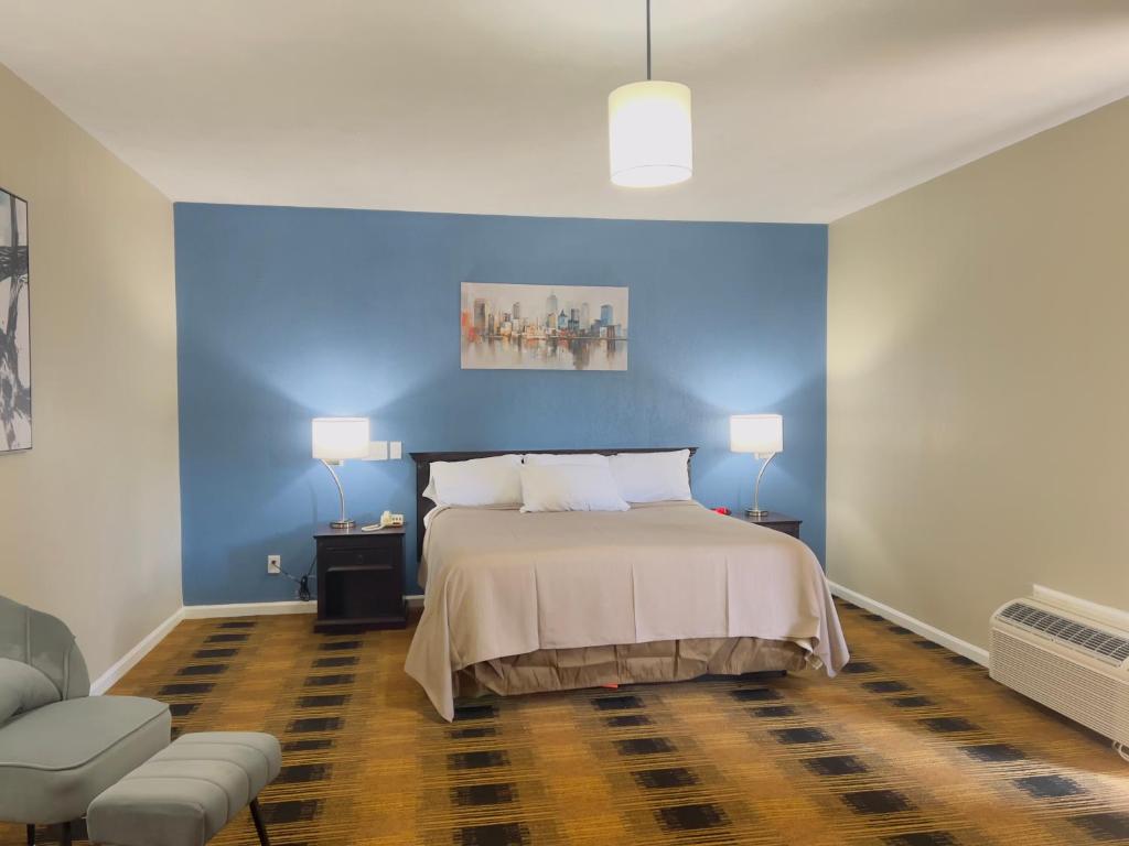 1 dormitorio con cama y pared azul en Budgetel Inn & Suites, en Dillard