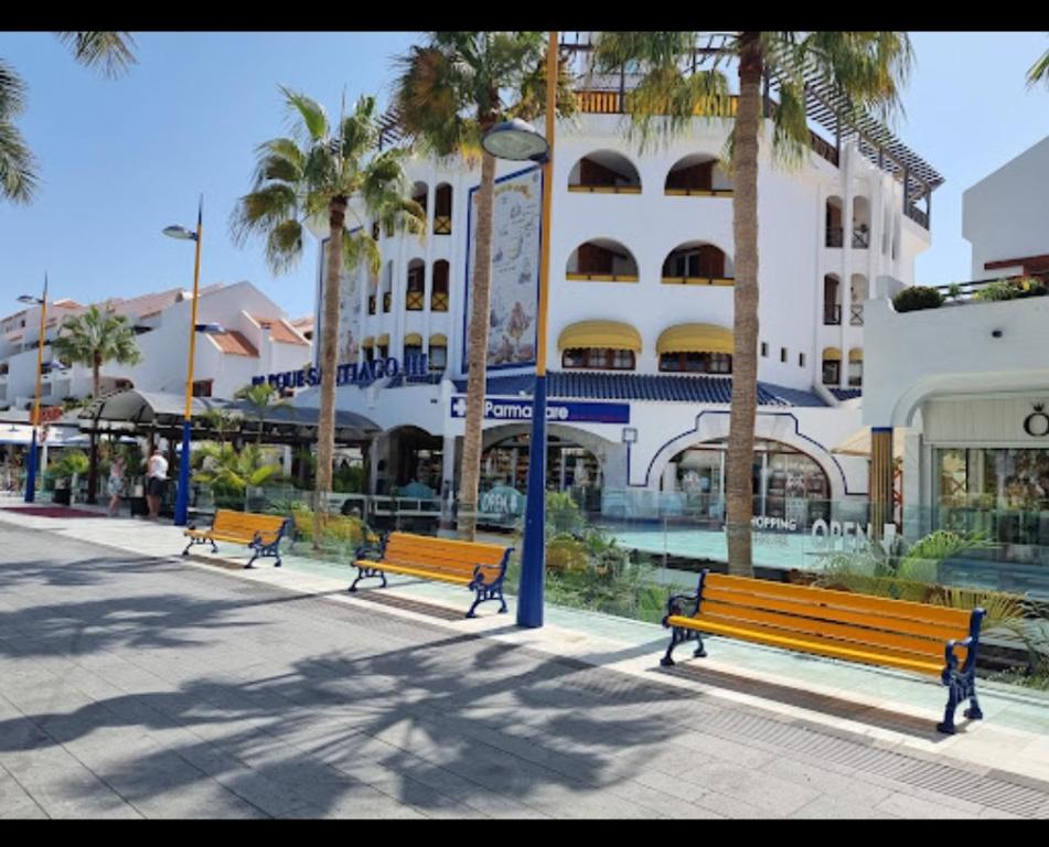 a row of park benches in front of a building at il centro delle vacanze in Playa de las Americas