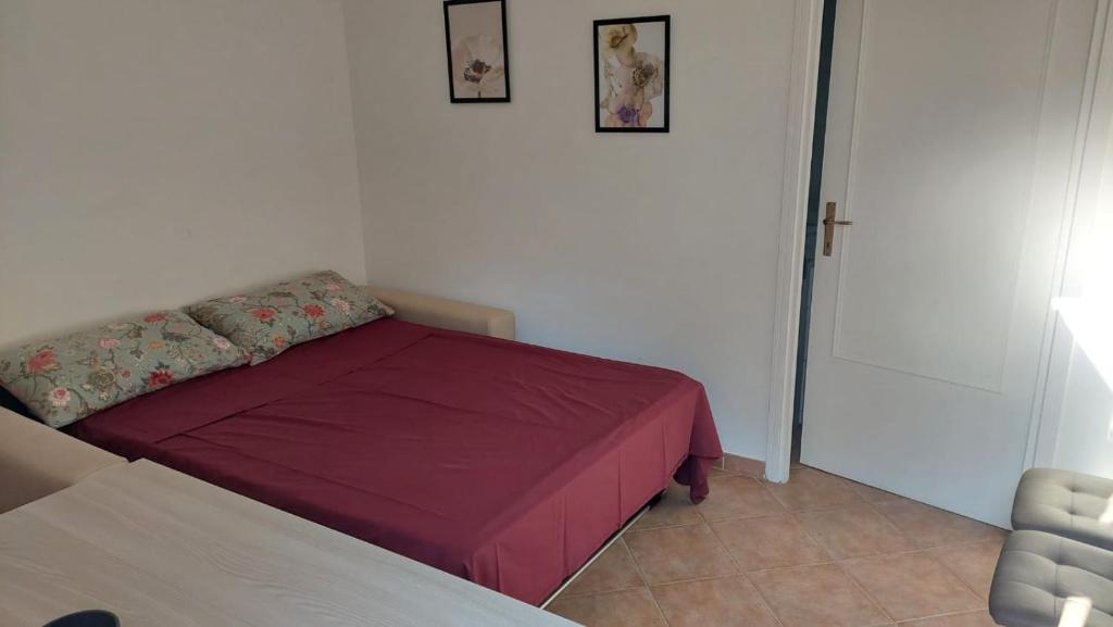 a small bedroom with a red bed with two pictures on the wall at La Passeggiata in Santa Marinella