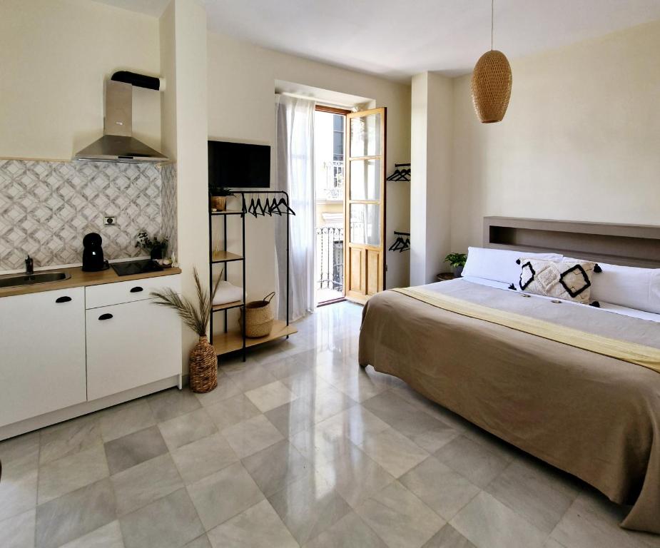 a bedroom with a large bed and a kitchen at Apartamentos VITA CENTER in Granada