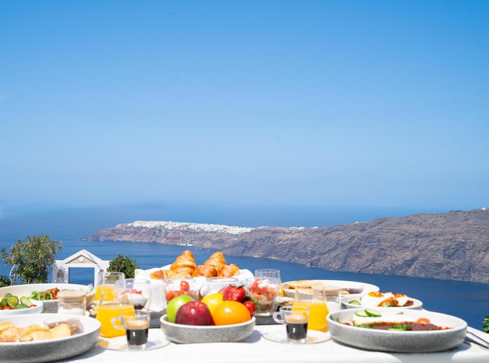 a table full of food with a view of the ocean at Saint Sin Suites - Adults Only in Imerovigli