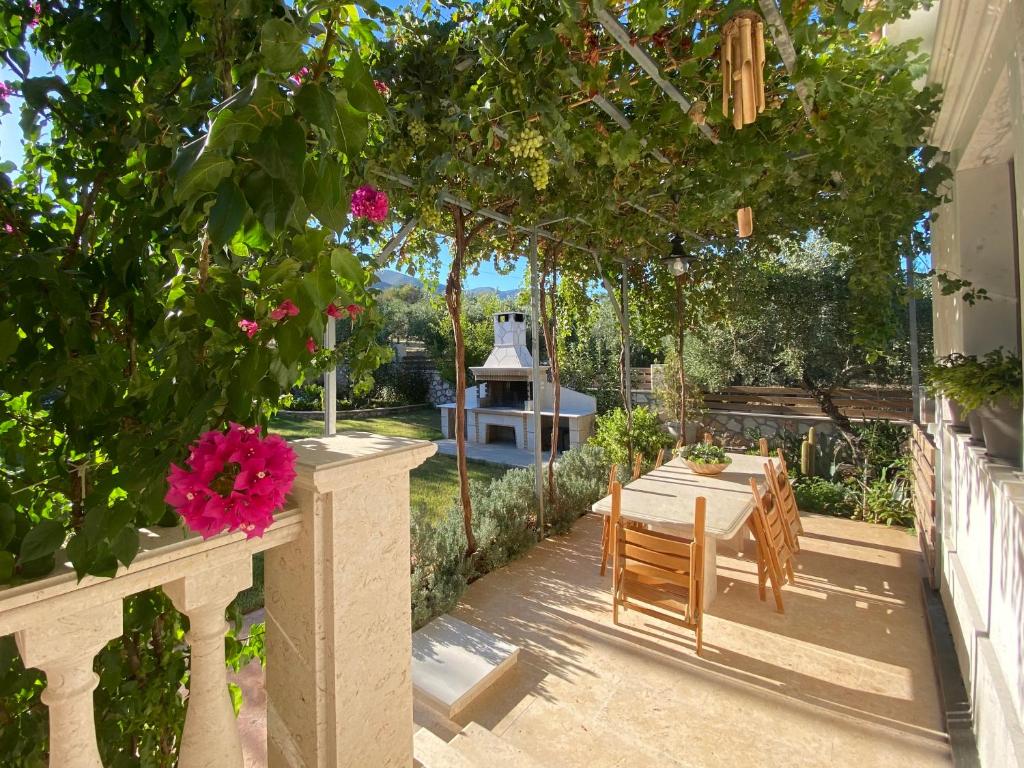 patio ze stołem, krzesłami i kwiatami w obiekcie Villa Serenity w mieście Agia Marina