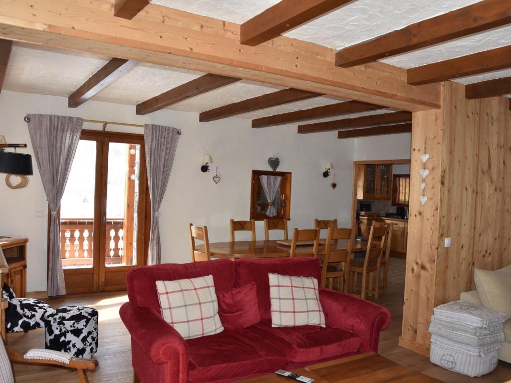 - un salon avec un canapé rouge et une salle à manger dans l'établissement Luxueux chalet ensoleillé, ski aux pieds, près des pistes et du centre. - FR-1-464-169, à Pralognan-la-Vanoise