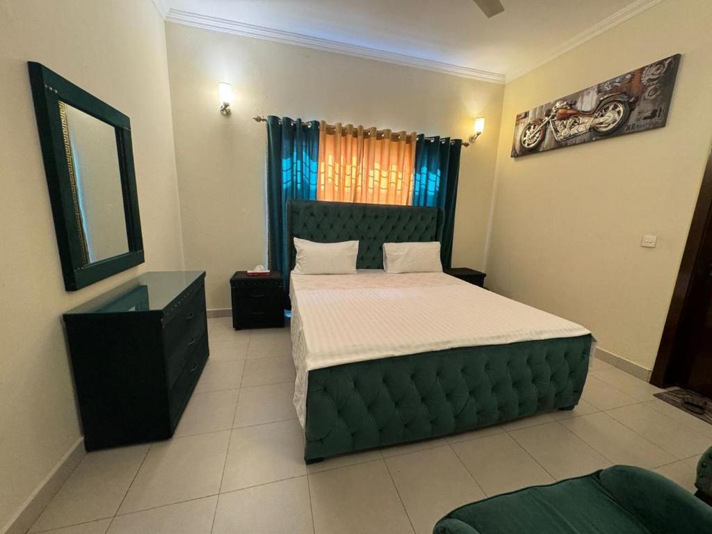 - une chambre avec un lit doté d'une tête de lit verte et d'un miroir dans l'établissement Holidazzle Villa, à Karachi