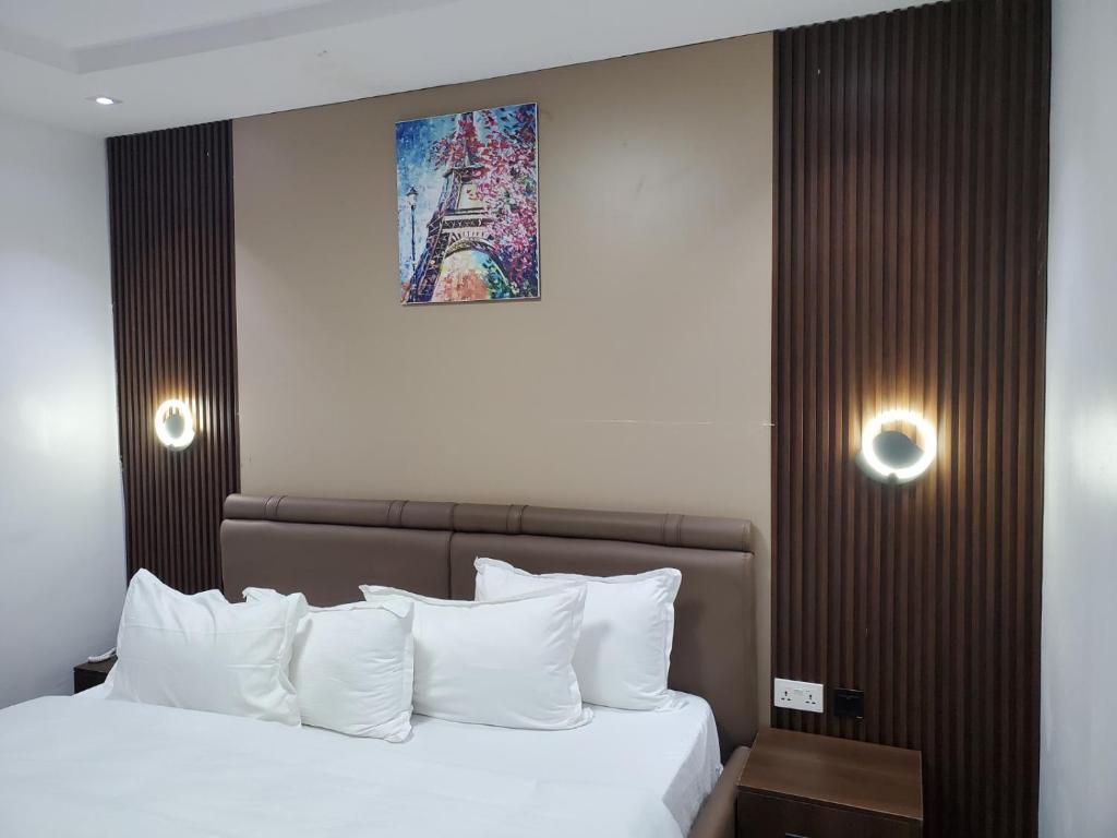 a bedroom with a bed with white pillows and a painting at Hotel Thirty Five in Lagos