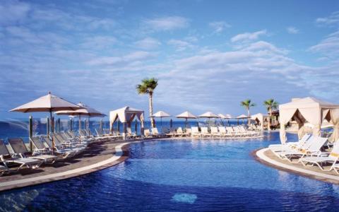 a large swimming pool with chairs and umbrellas at Sunset Beach golf & spa Resort Pueblo Bonito in Cabo San Lucas