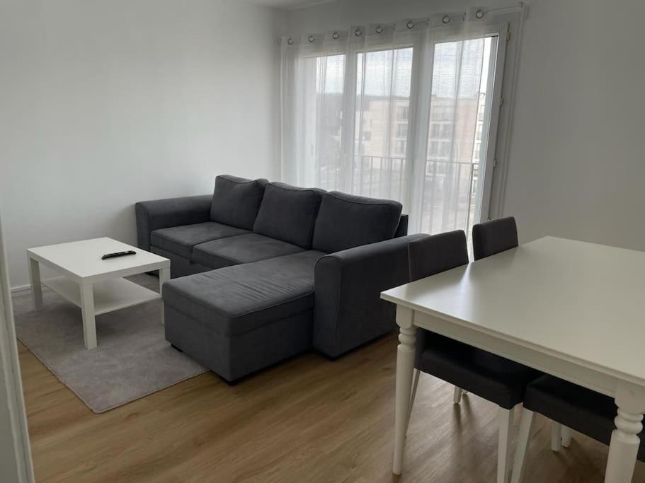 uma sala de estar com um sofá e uma mesa em Appartement spacieux et cosy 20 min to Paris & JO 2024 em Sannois