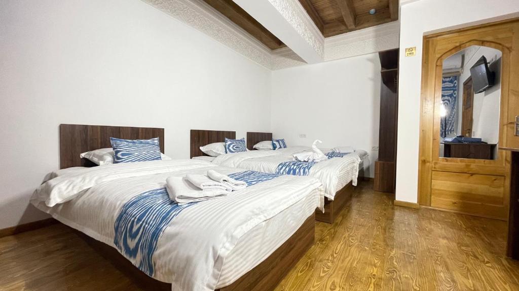 2 camas en una habitación con sábanas blancas y azules en Mahbubakhon Hotel, en Bukhara