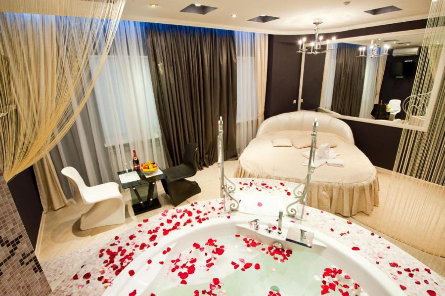 a bedroom with a bed and a tub filled with red flowers at Style Hotel in Kharkiv