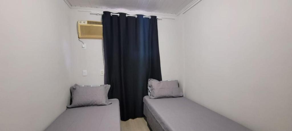 um pequeno quarto com duas camas e uma cortina em Casa ao lado da Dubai brasileira em Camboriú
