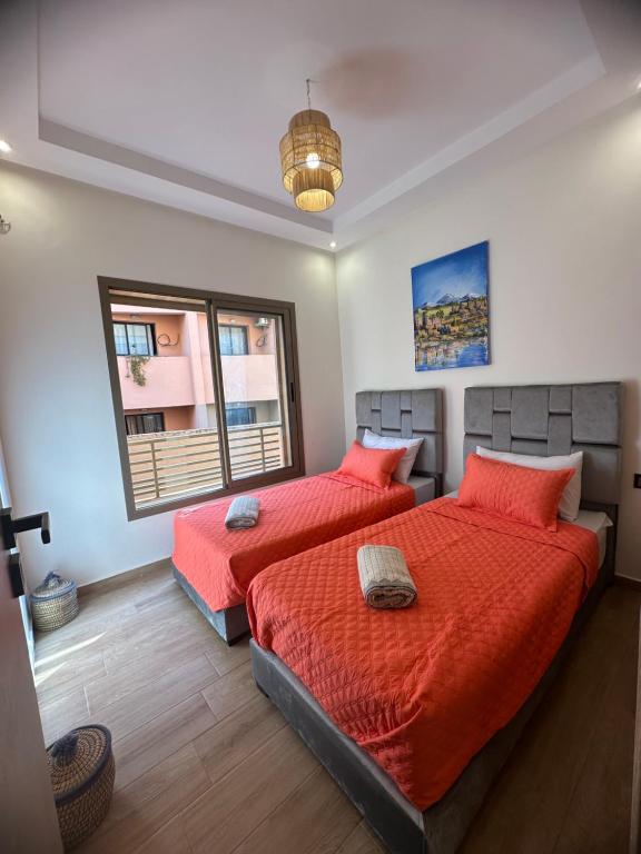 1 dormitorio con 2 camas y ventana en Brand New Modern 2 BR Apartment with Swimming Pool, Netflix & IPTV en Marrakech