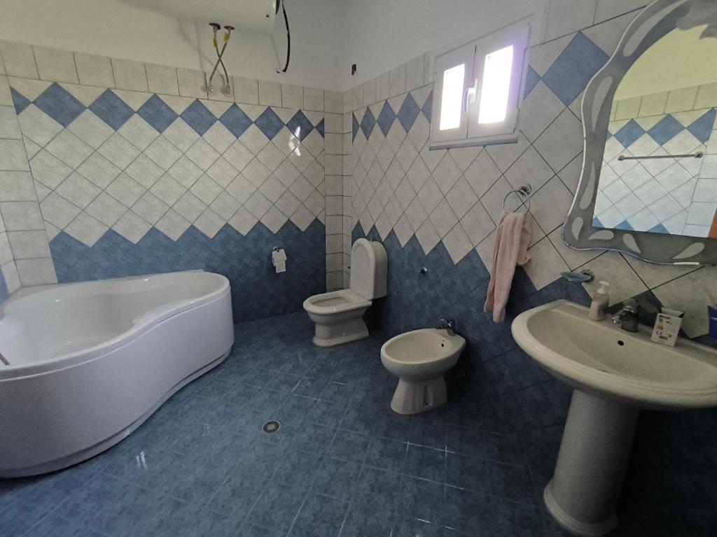 a bathroom with a tub and a toilet and a sink at Villa Lediana in Delvinë