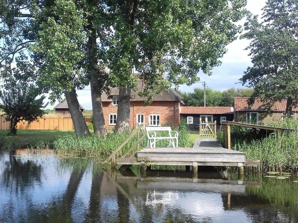 uma mesa e cadeiras sentadas numa doca num lago em 6 Bed in Wroxham 72652 em Hoveton