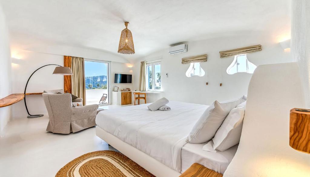 a white bedroom with a large bed and a chair at Villa Ravino Aparthotel in Ischia
