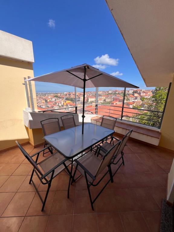 un tavolo con sedie e un ombrellone su un balcone di Villetta panoramica con giardino a Ossi