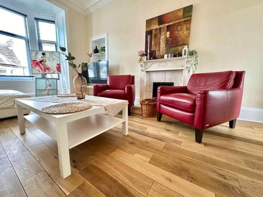 een woonkamer met 2 rode stoelen en een open haard bij Dumbarton cosy home, Loch Lomond in Dumbarton