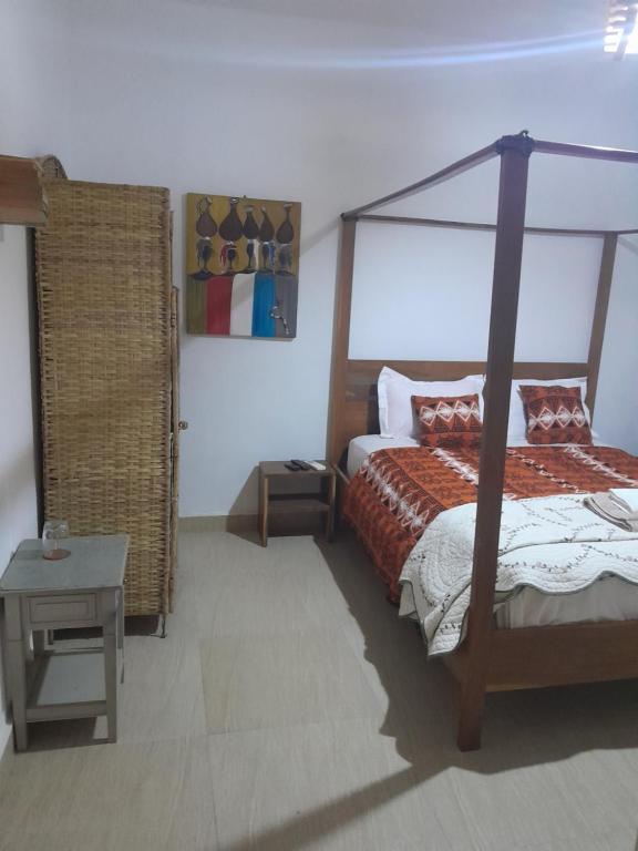 a bedroom with a canopy bed and a table at Pied a terre in Ouakam in Ouakam