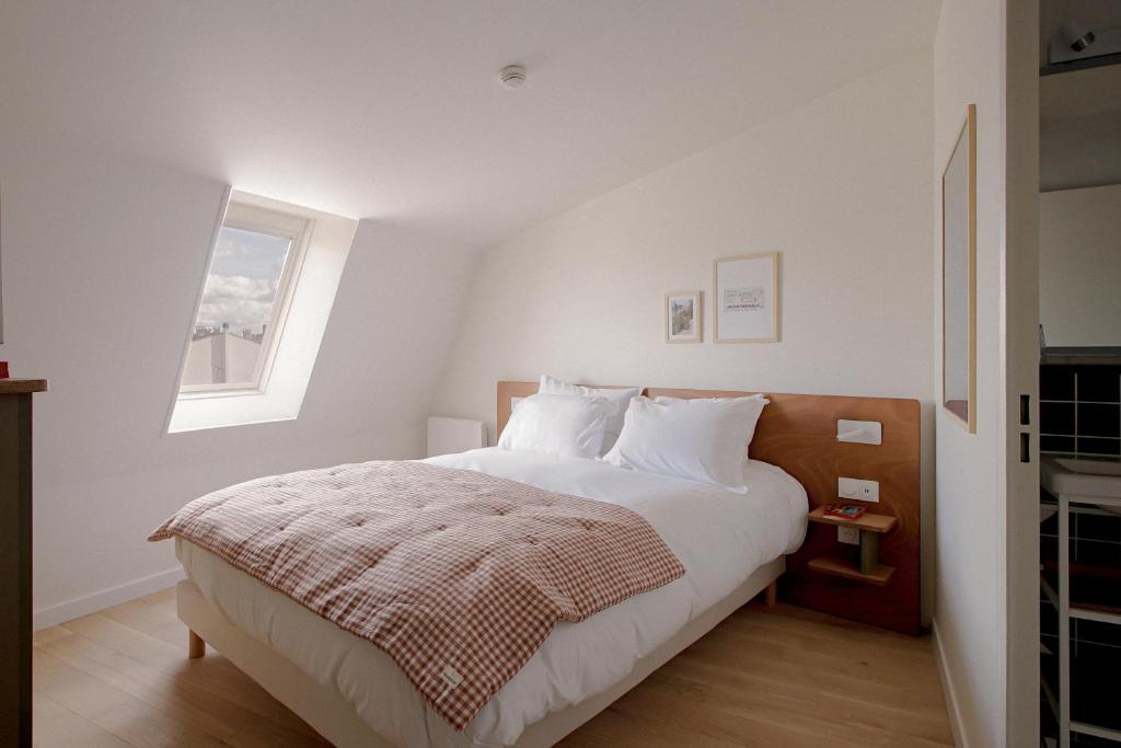 um quarto com uma cama com lençóis brancos e uma janela em ALFRED HOTELS Compiègne Ex Hôtel des Beaux-Arts em Compiègne
