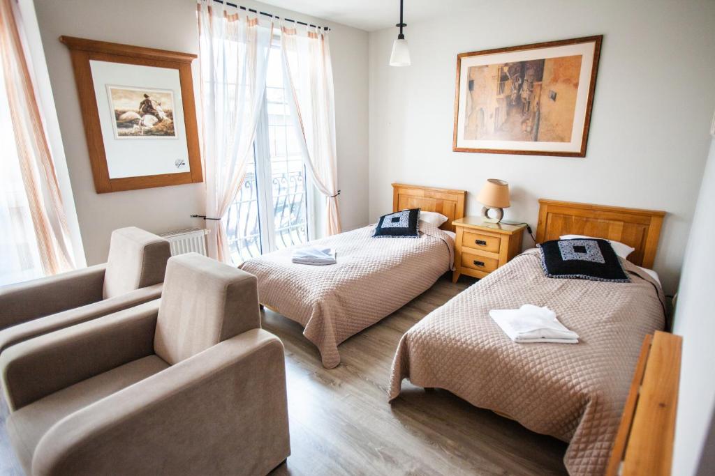 1 dormitorio con 2 camas, sofá y ventana en Pokoje Przy Plaży, en Mielno