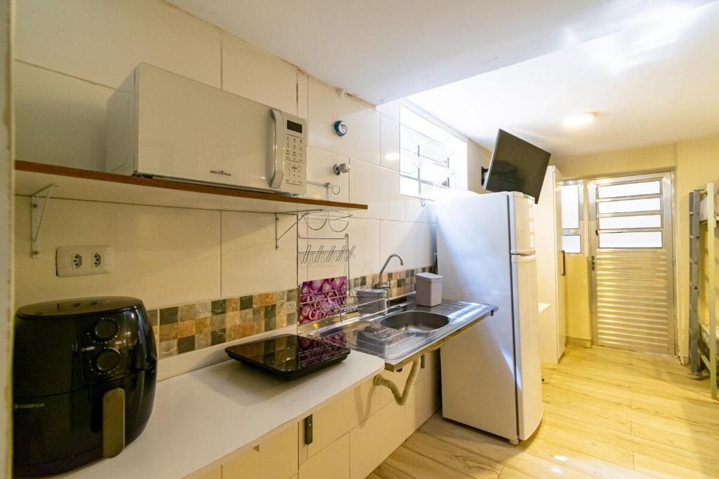 a kitchen with a white refrigerator and a sink at 30 Studio Sextuplo · Studio perto da Expo São Paulo/Centro Paraolímpico in Sao Paulo