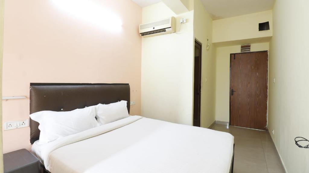 a bedroom with a white bed and a brown door at ROYAL PARK NEAR BELLANDHUR,HSR in Bangalore
