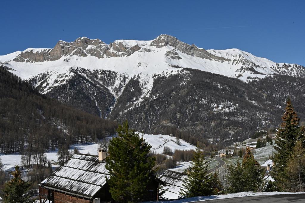 una montaña cubierta de nieve con una casa en el primer plano en Les Airelles 33, Le coin, Molines en Queyras Classé 3 étoiles en Molines-en-Queyras