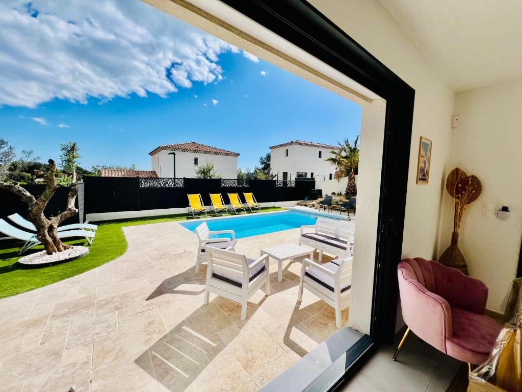 un patio avec une table et des chaises et une piscine dans l'établissement Villa Mila*Proche plages, à La Garde