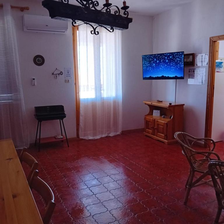 uma sala de estar com uma televisão e uma mesa e cadeiras em A due passi dal mare em Codaruina