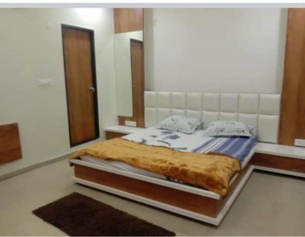 - une chambre avec un lit et un grand miroir dans l'établissement Abhinandan guesthouse, à Gondia