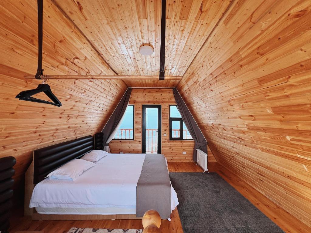 a bedroom with a large bed in a wooden room at ALTO Cabins in Alamedin